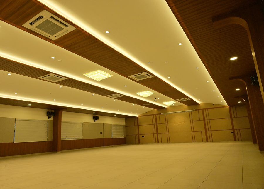 Spacious banquet hall at Bhavanis Vista By Icon Hosur with layered false ceiling, cove lighting, and mirrored side wall.