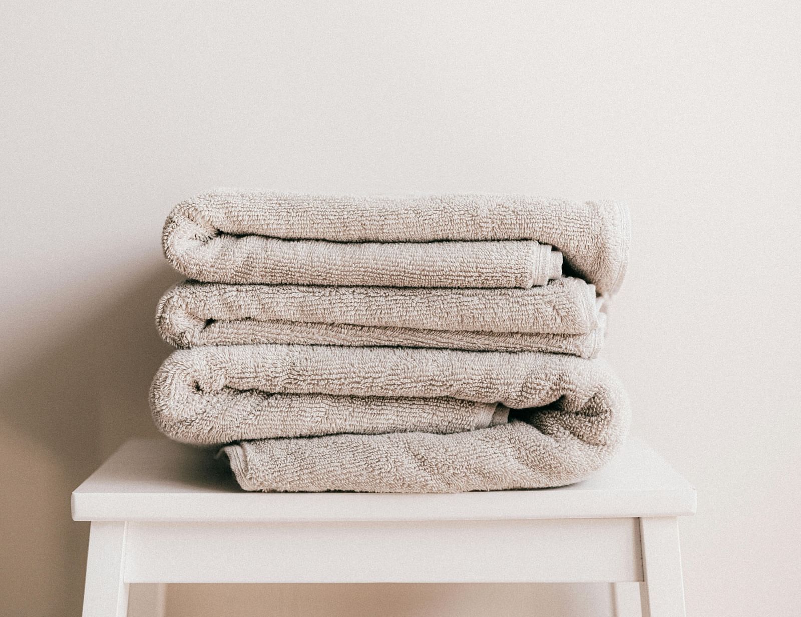 a few white coloured towels neatly folded and kept on a stool