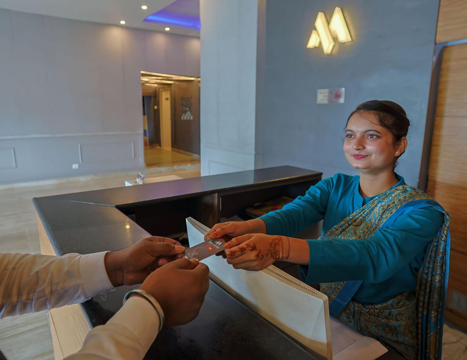 Guest sitting area with staff handing a document at Max Hotel Prayagraj.