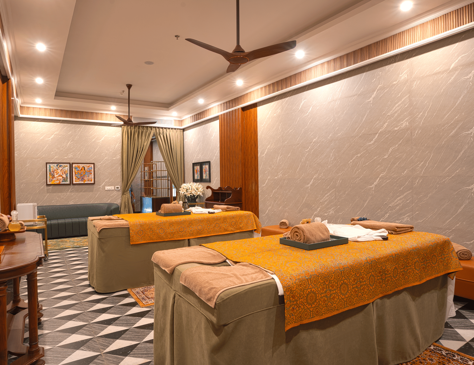 2 massage beds covered in orange towels in a spa room, with calming green and yellow accents at MAYFAIR Bay Resort, Paradeep.