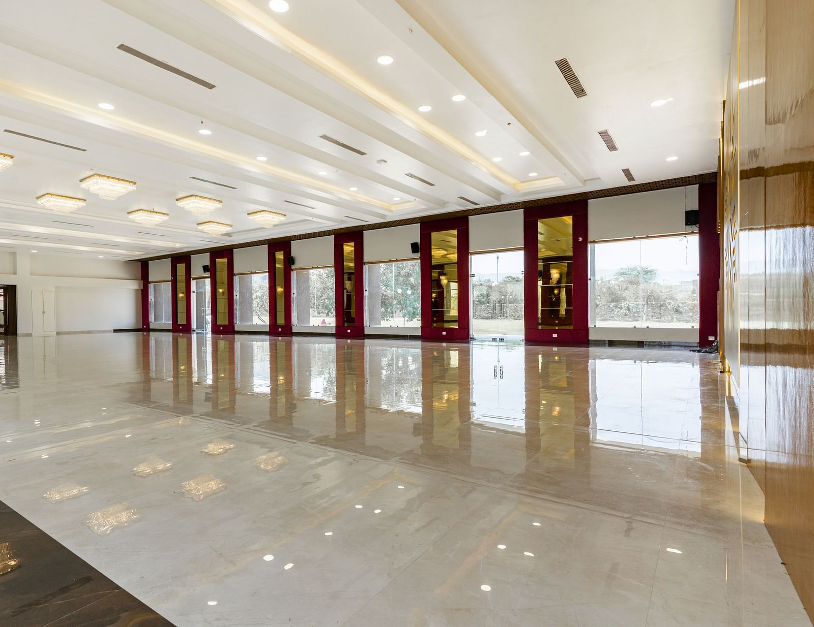 A slightly different angle of a long, empty hallway with a highly polished floor reflecting the ceiling and walls - Bamboo Saa Mulberry Resort, Pushkar
