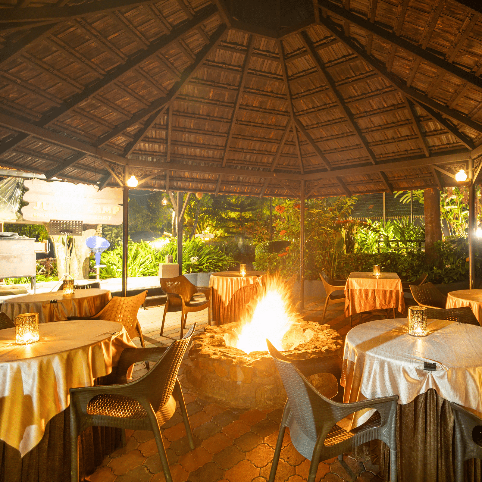 A dining space with a bonfire in the middle at Coorg Jungle Camp Backwater Resort, Kushalnagar.