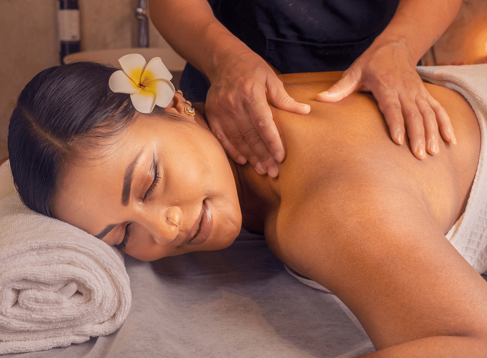  A woman receiving a soothing massage, surrounded by soft lighting and fresh flowers. The calm setting helps create a peaceful, spa-like experience - Coral Reef Resort & Spa, Havelock