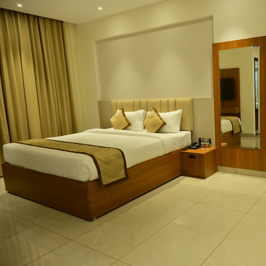 Bedroom of Bhavanis Vista By Icon featuring a bed, a headboard, an armchair, and a mirror.