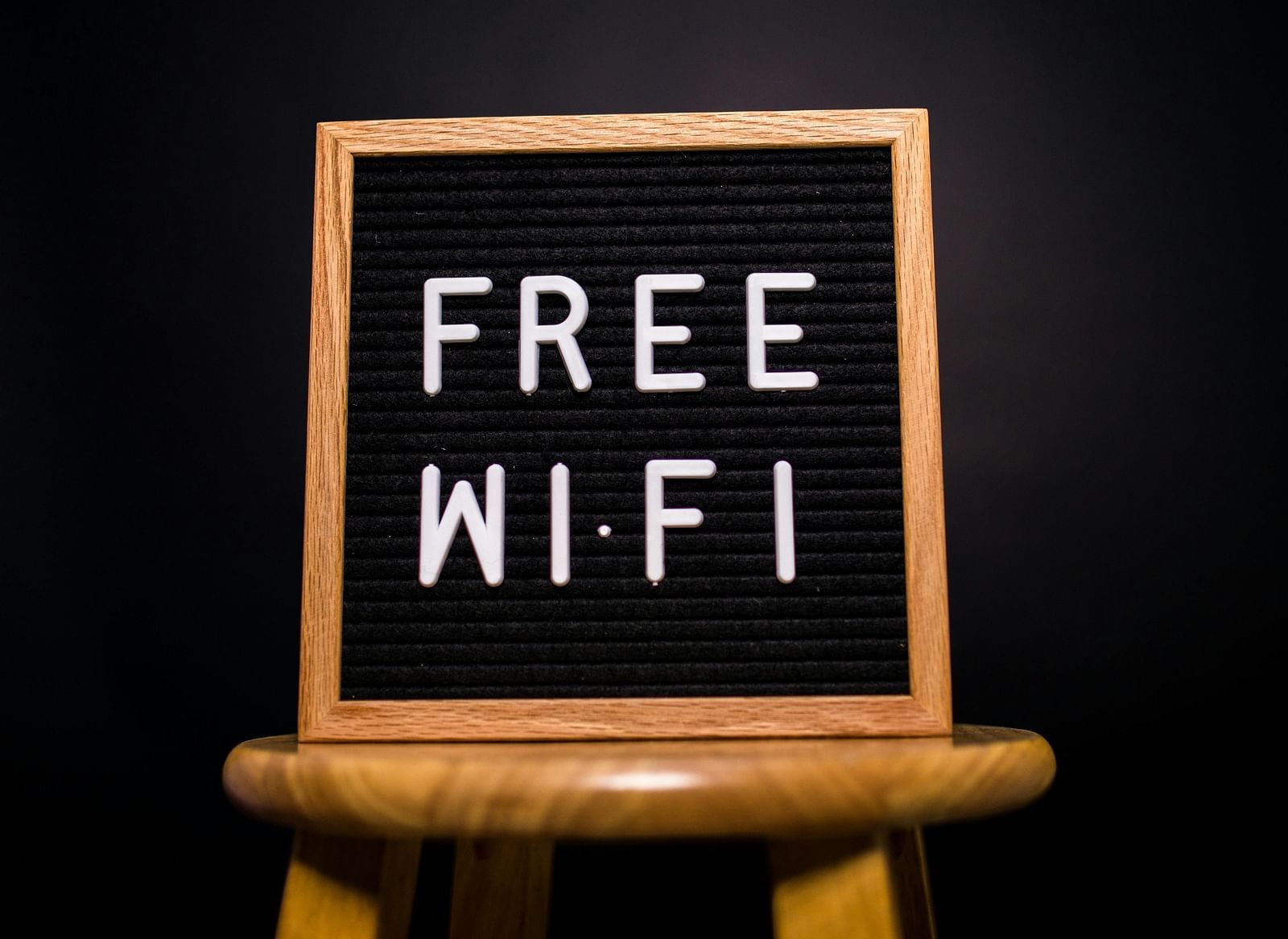 A board on a small wooden stool displaying FREE WI-FI against a dark background.