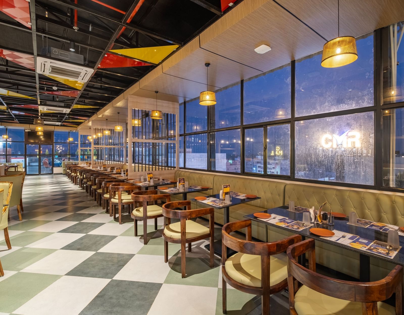 Bright dining hall at Monday Hotels Amalapuram Heights with large glass windows.