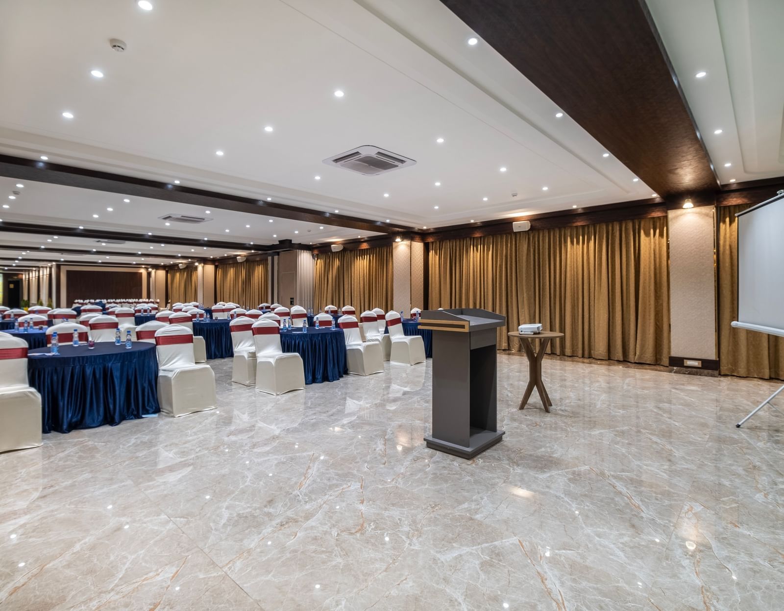 Event hall at Monday Hotels Amalapuram Heights arranged with cluster style seating and stage podium.