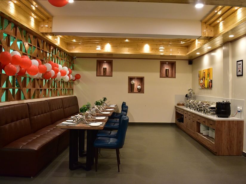 side angle view of dining table of a tea-seater dining table situated in front of the buffet area and decorated with red and white balloons - Hotel Montana Vyoo