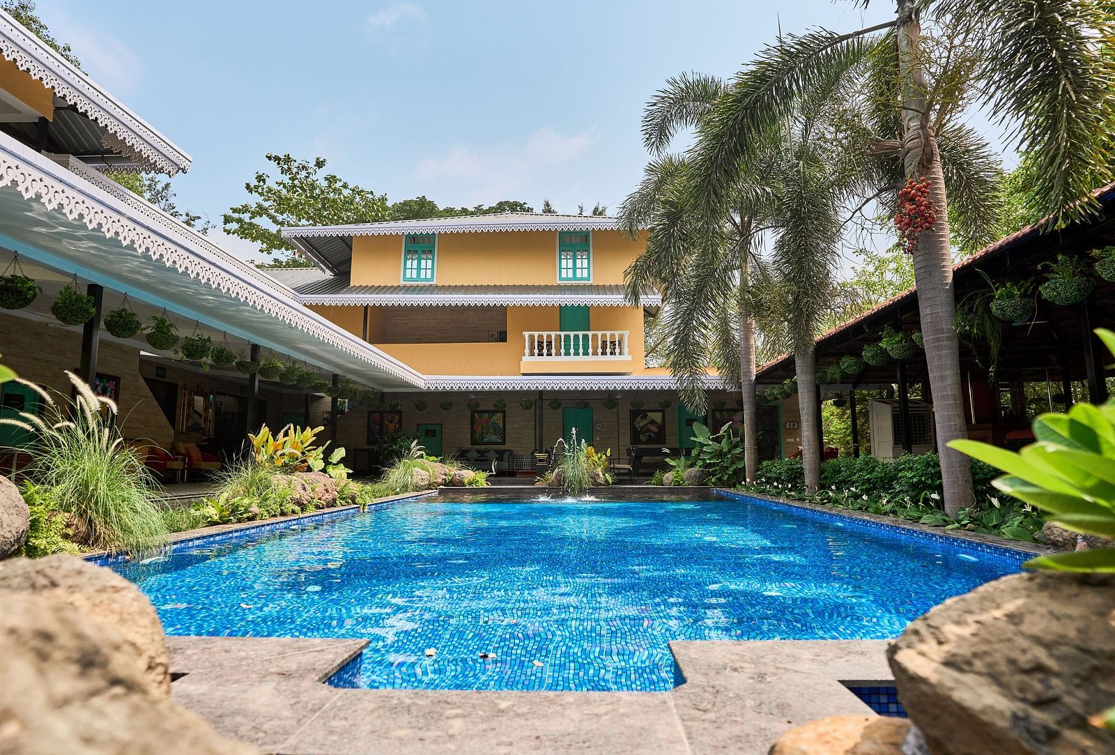 Swimming pool with a facade, surrounded by plants and trees at Mayfair Manor, Alibag