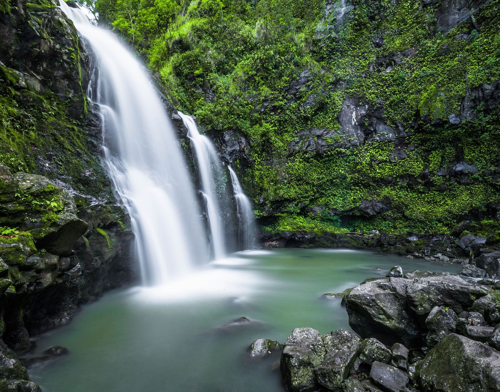 a waterfall cascading down to a waterbody with trees on either side