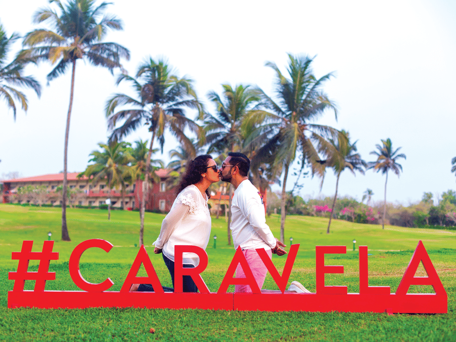 a couple kissing in front of a #Caravela sign - Caravela Beach Resort Goa
