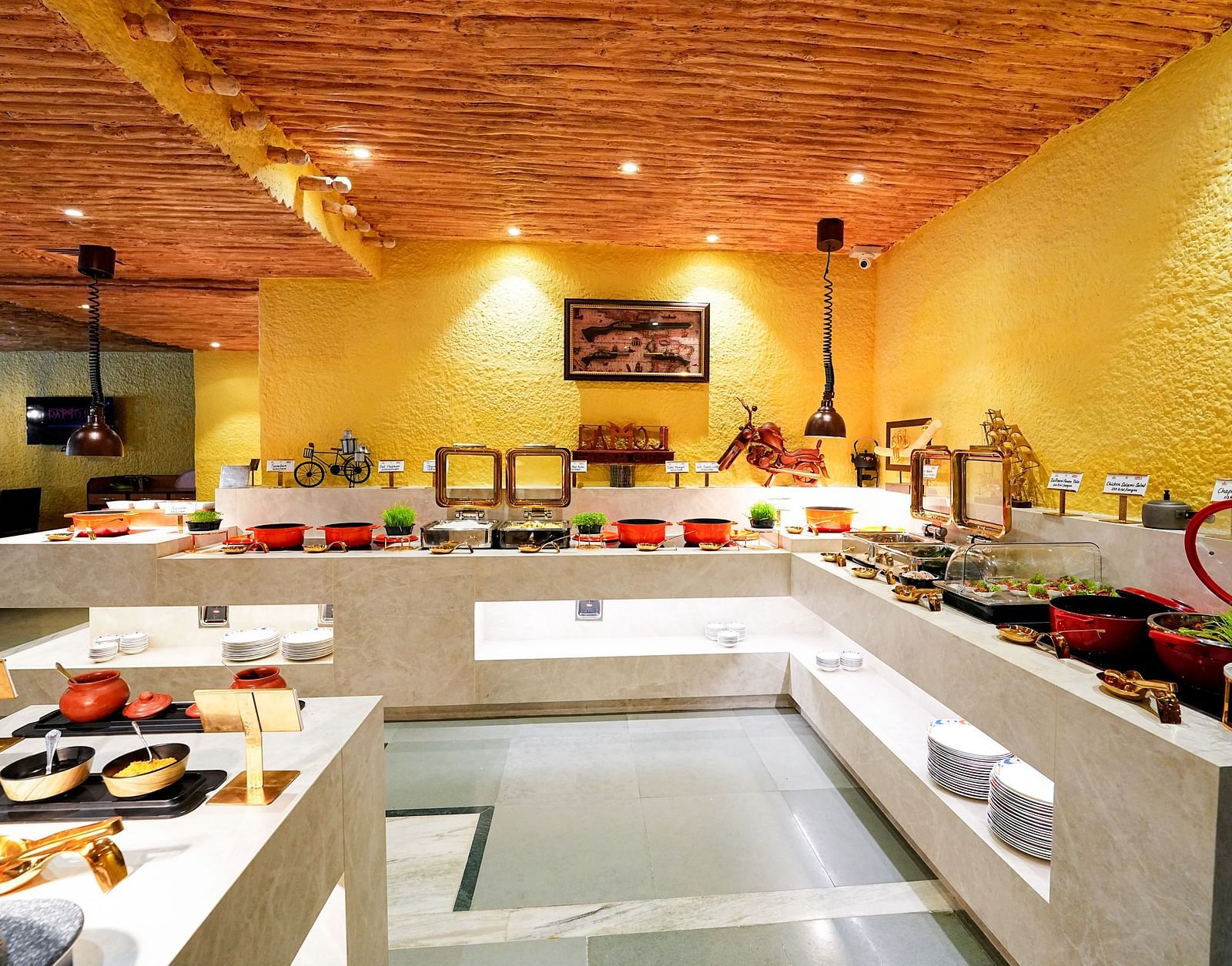 A comprehensive view of a buffet setup in a room with a rustic ceiling and yellow walls. - Tara, Comfort Hotel in Hyderabad - Ramoji Film City.
