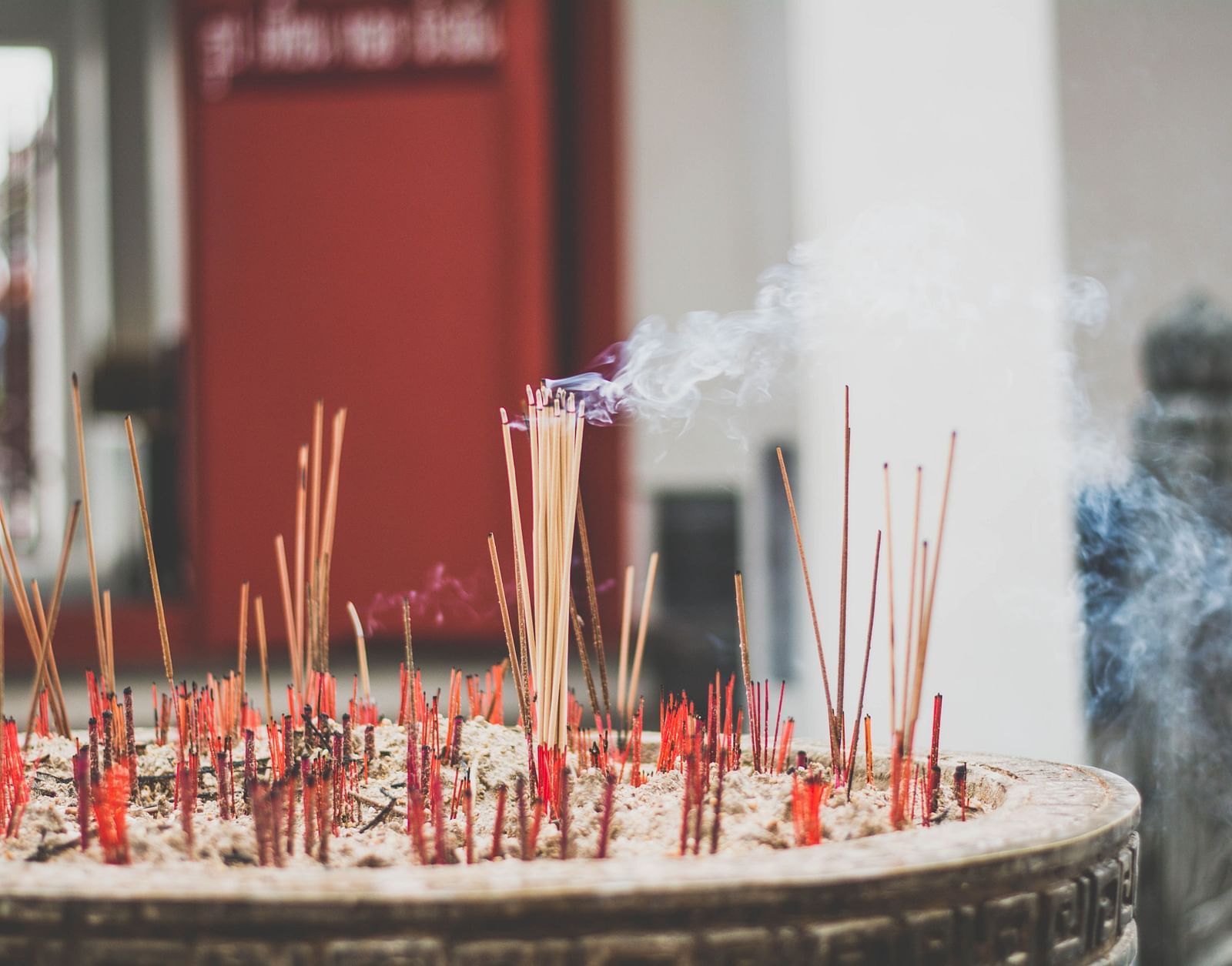 many lit incense sticks kept on a bowl of sand 