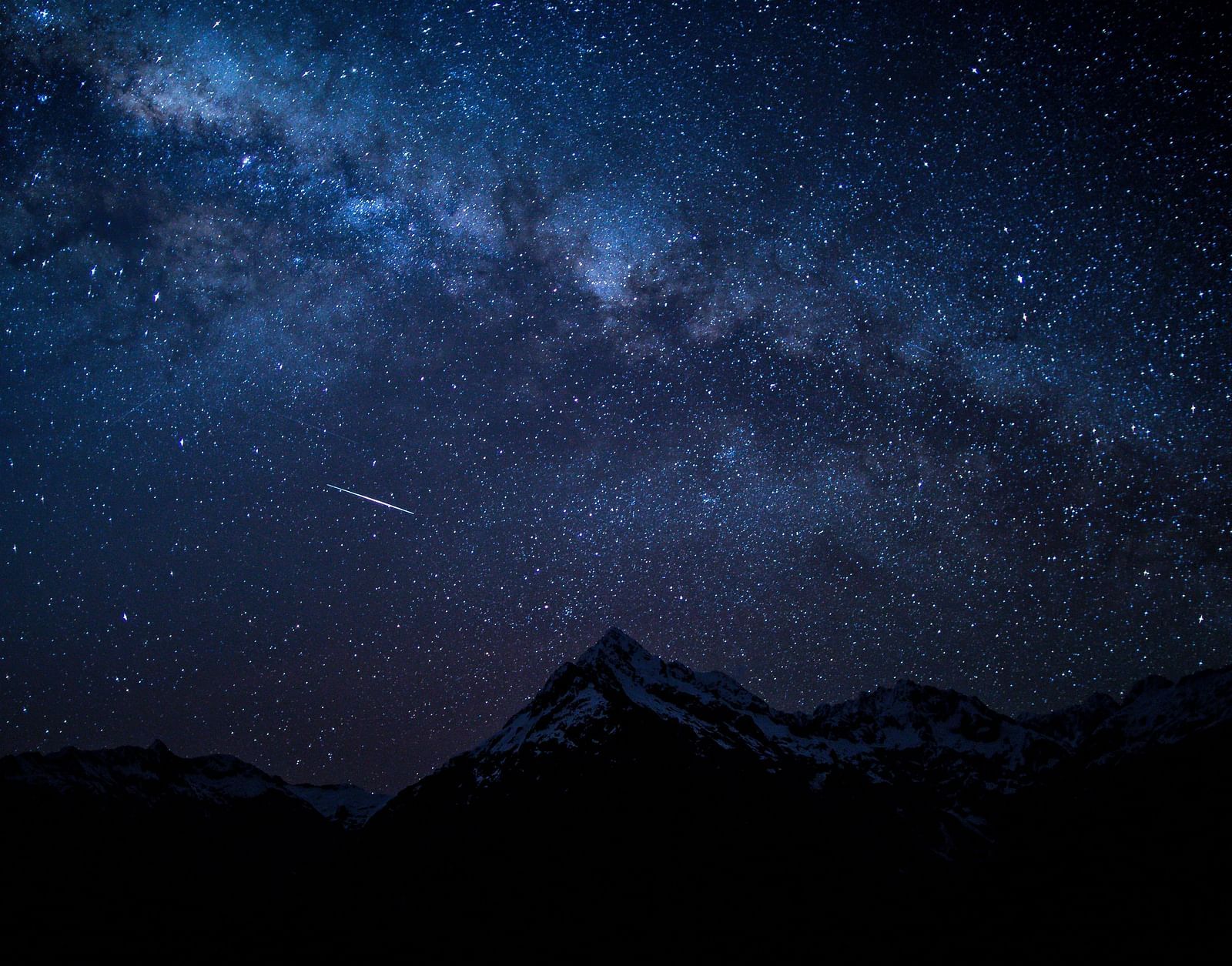 a star lit sky with mountains in the foreground
