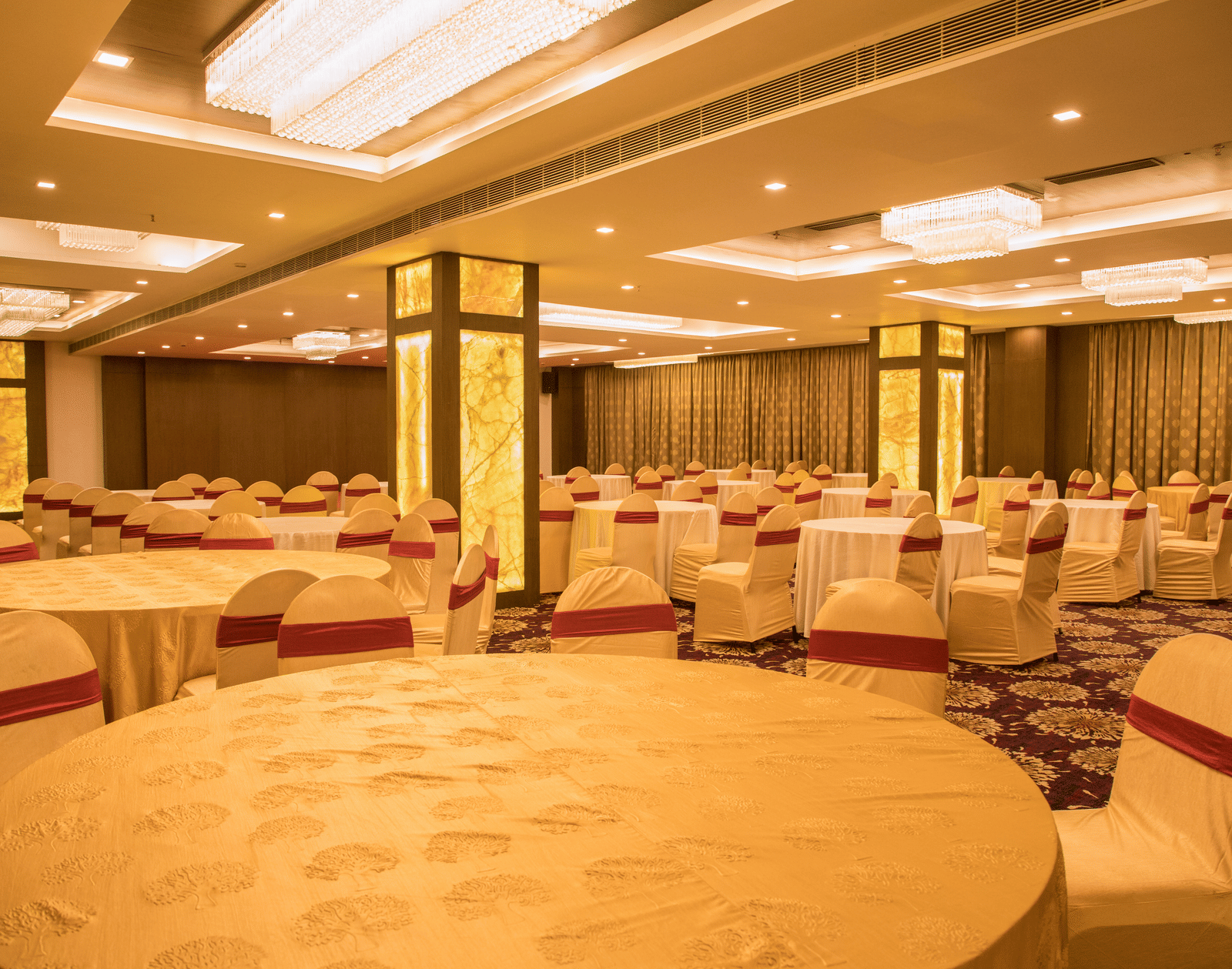 A large banquet hall at Benzz Park Chennai with multiple round tables and chairs, ready for a function.