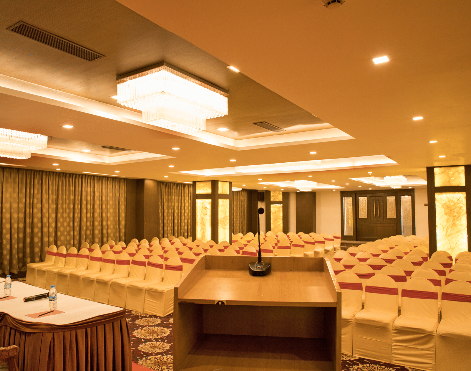A conference room at Benzz Park Chennai set up with rows of tables and chairs, facing a podium.