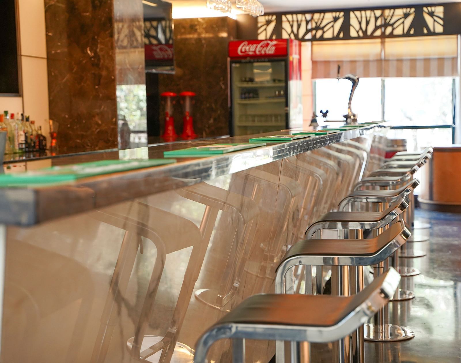 nother perspective of a well-appointed bar at BNGV Grandeur Hotel and Banquets, showcasing bottles lined up behind the counter and ample bar seating.