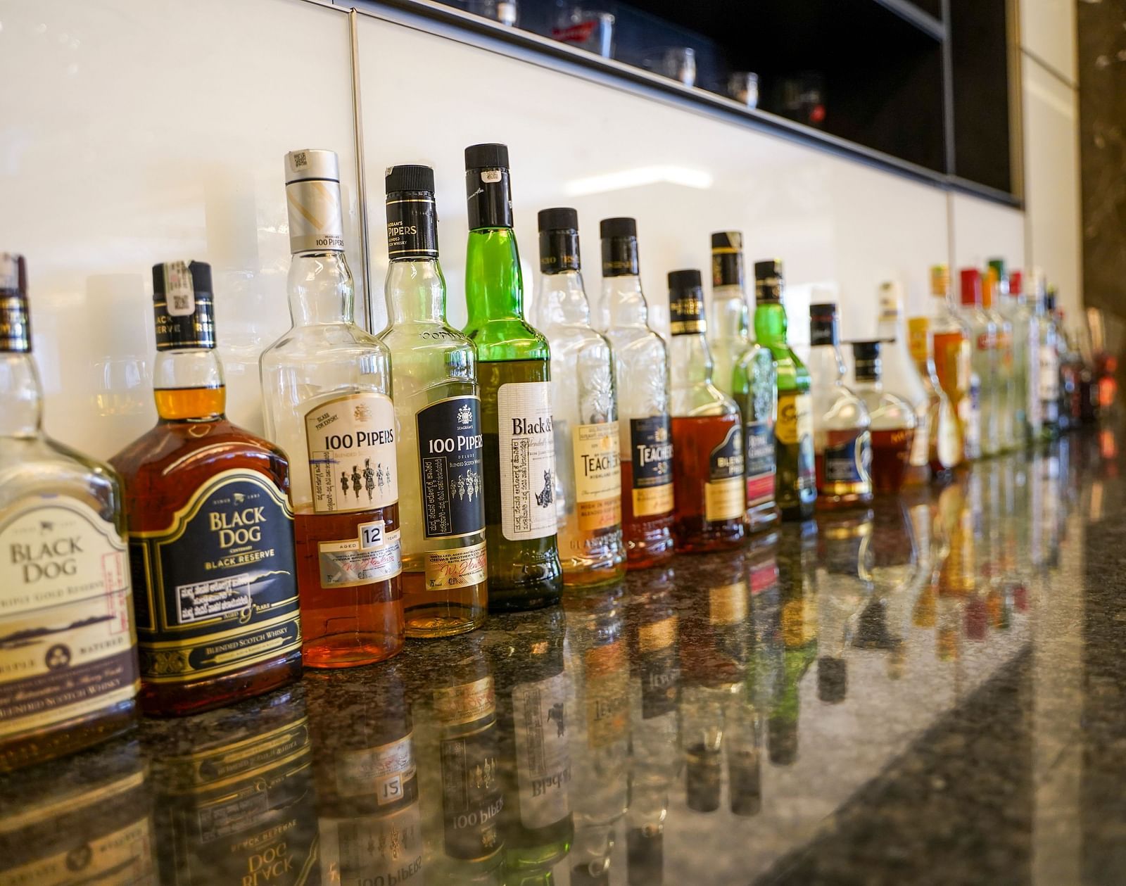 A close-up of a well-stocked bar counter at BNGV Grandeur Hotel and Banquets, displaying various bottles of liquor and spirits.