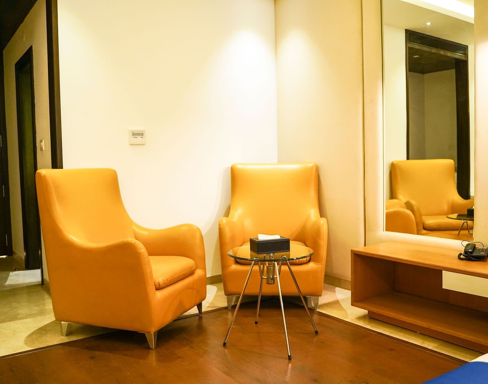  A cosy and inviting lounge area within BNGV Grandeur Hotel and Banquets, showcasing two comfortable orange armchairs and a small table, ideal for relaxation.