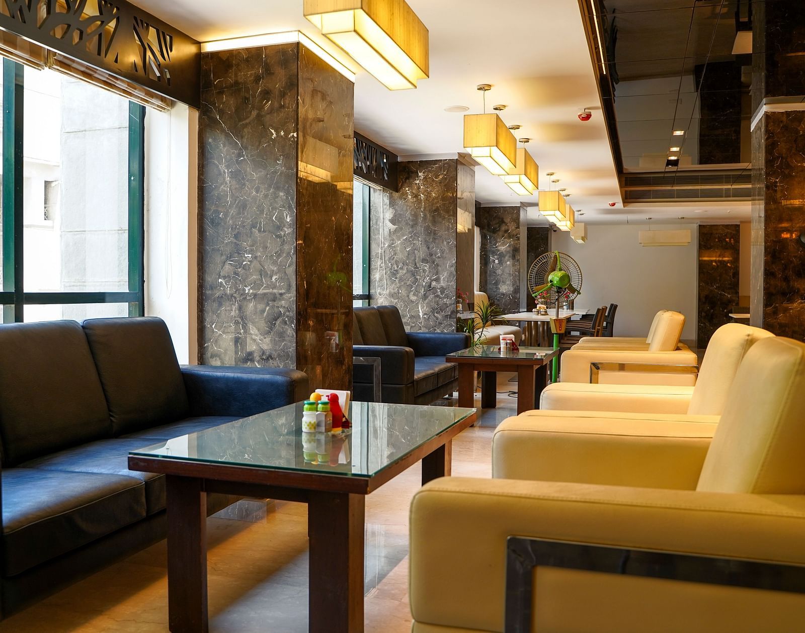 A wide shot of the elegant restaurant and seating area at BNGV Grandeur Hotel and Banquets, showcasing the arrangement of furniture and decorative elements.