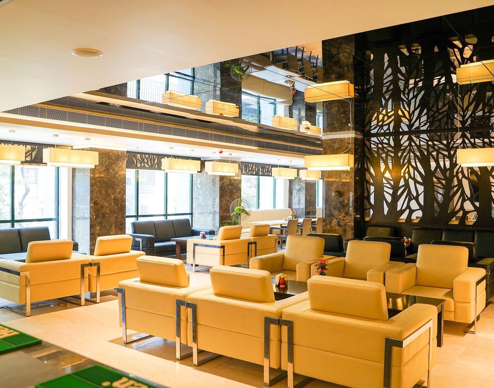 A bright and modern lounge area with light-colored seating and decorative elements, located within BNGV Grandeur Hotel and Banquets.