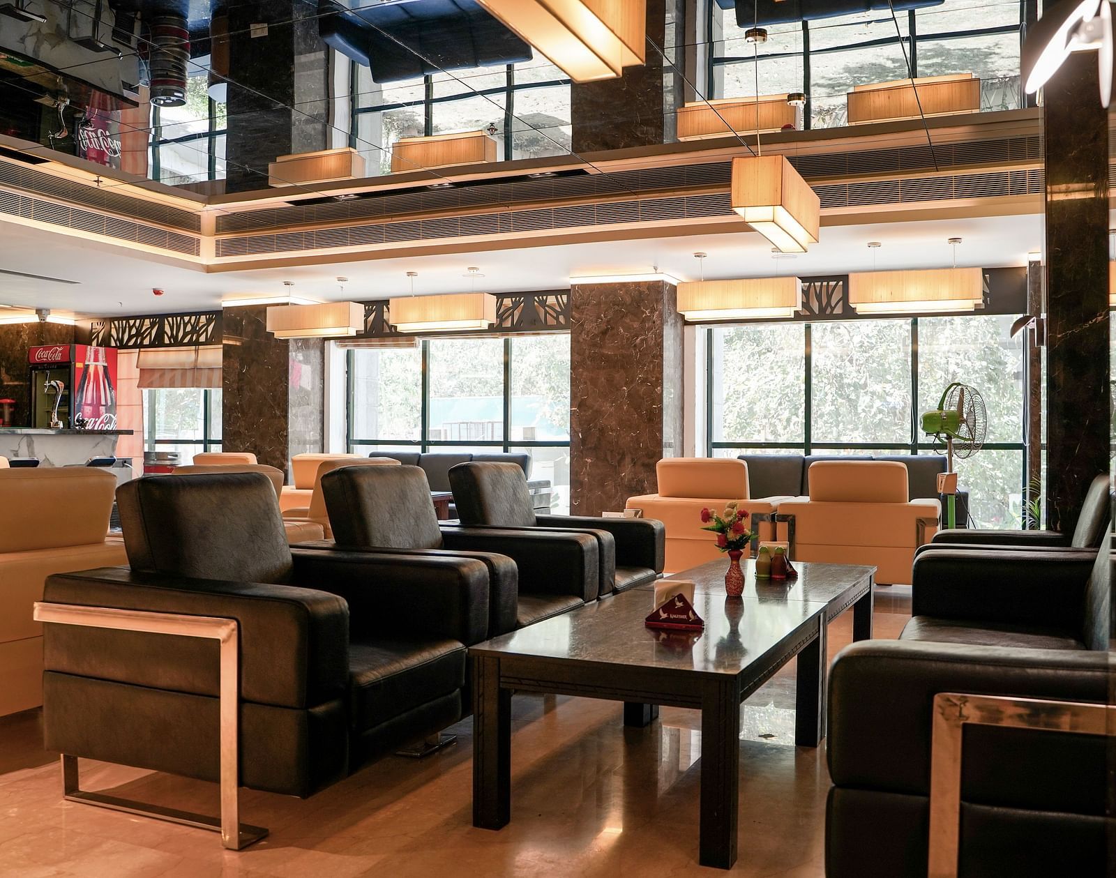 A stylish dining area at BNGV Grandeur Hotel and Banquets with multiple tables and chairs, featuring contemporary lighting fixtures and reflective ceiling elements.