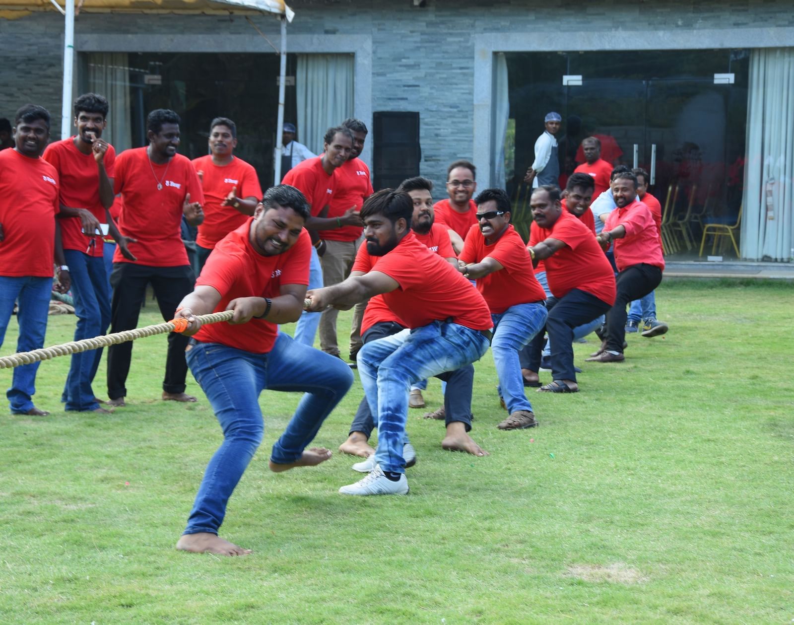 Group of people with red t-shirts pulling on opposite ends of a rope competing for a tug of war game at Grande Bay Resort & Spa.