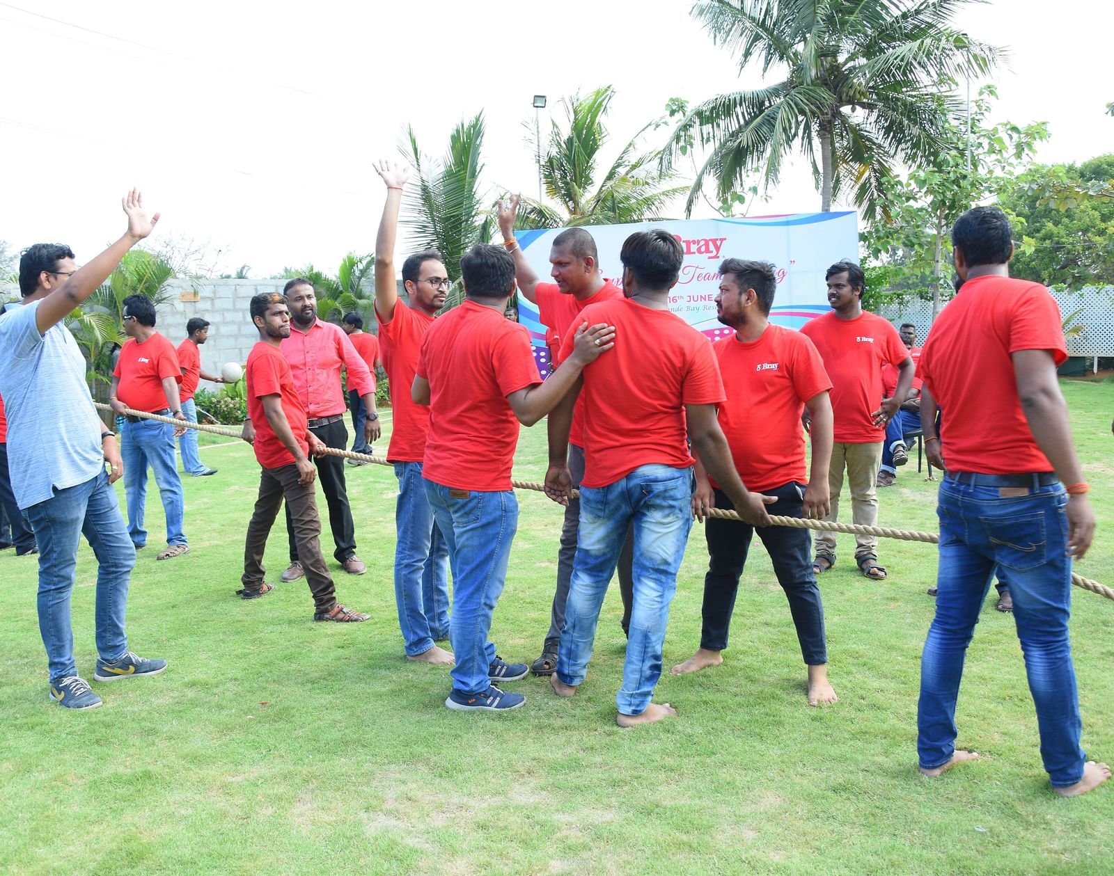 Group of people wearing red t-shirts standing with a rope on their hand in an outdoor space at Grande Bay Resort & Spa.