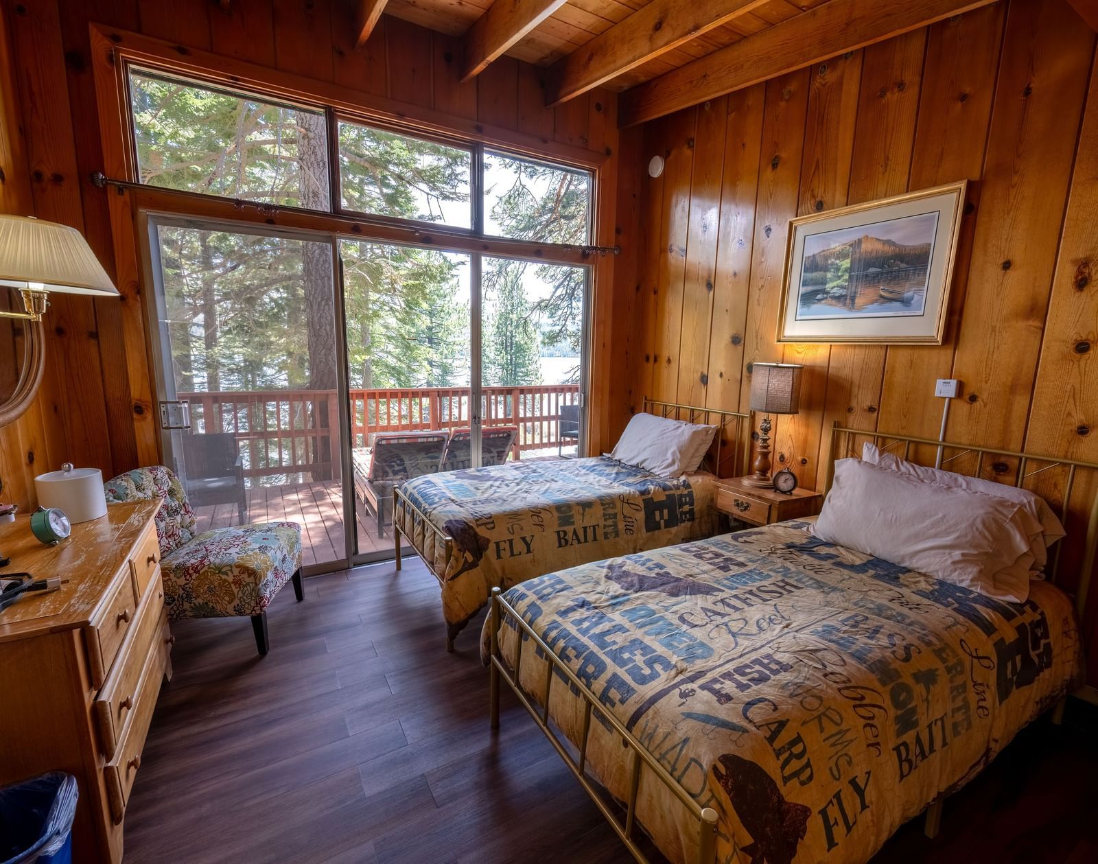 Double bed with forest views through large windows in a warmly lit wood-paneled room at Kit Carson Lodge.