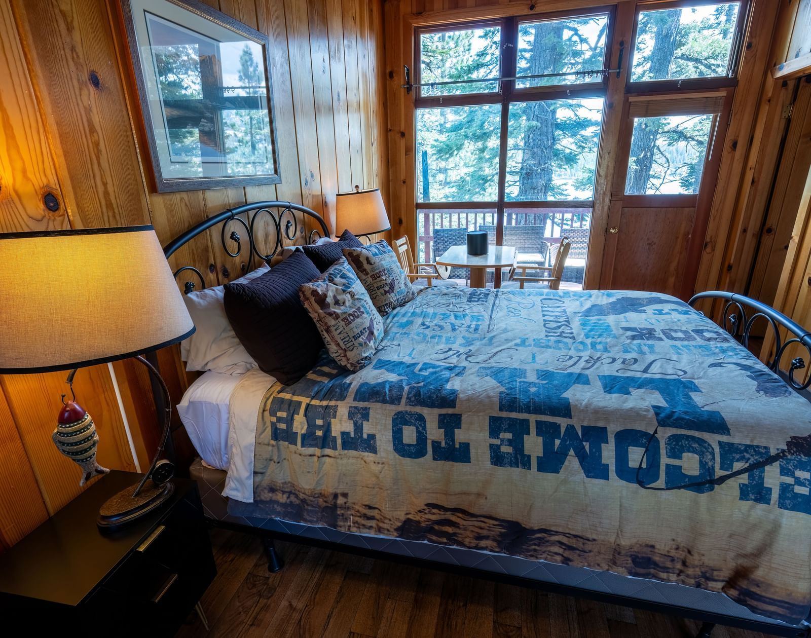 Bedroom with large windows, lake views, and cozy quilt at Kit Carson Lodge.