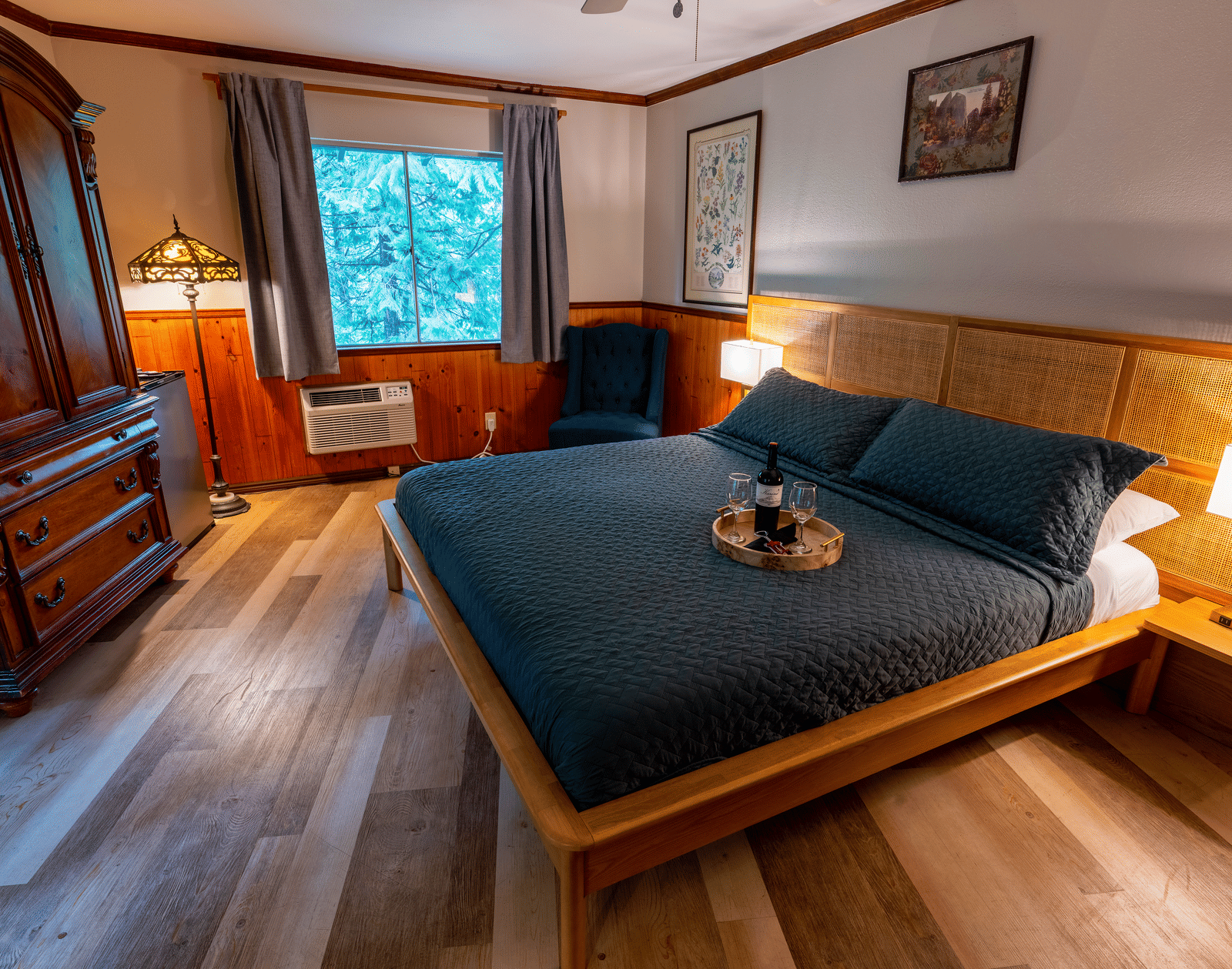 Cozy guest room at Narrow Gauge Inn featuring dark blue bedding, wooden furniture, and warm lighting.