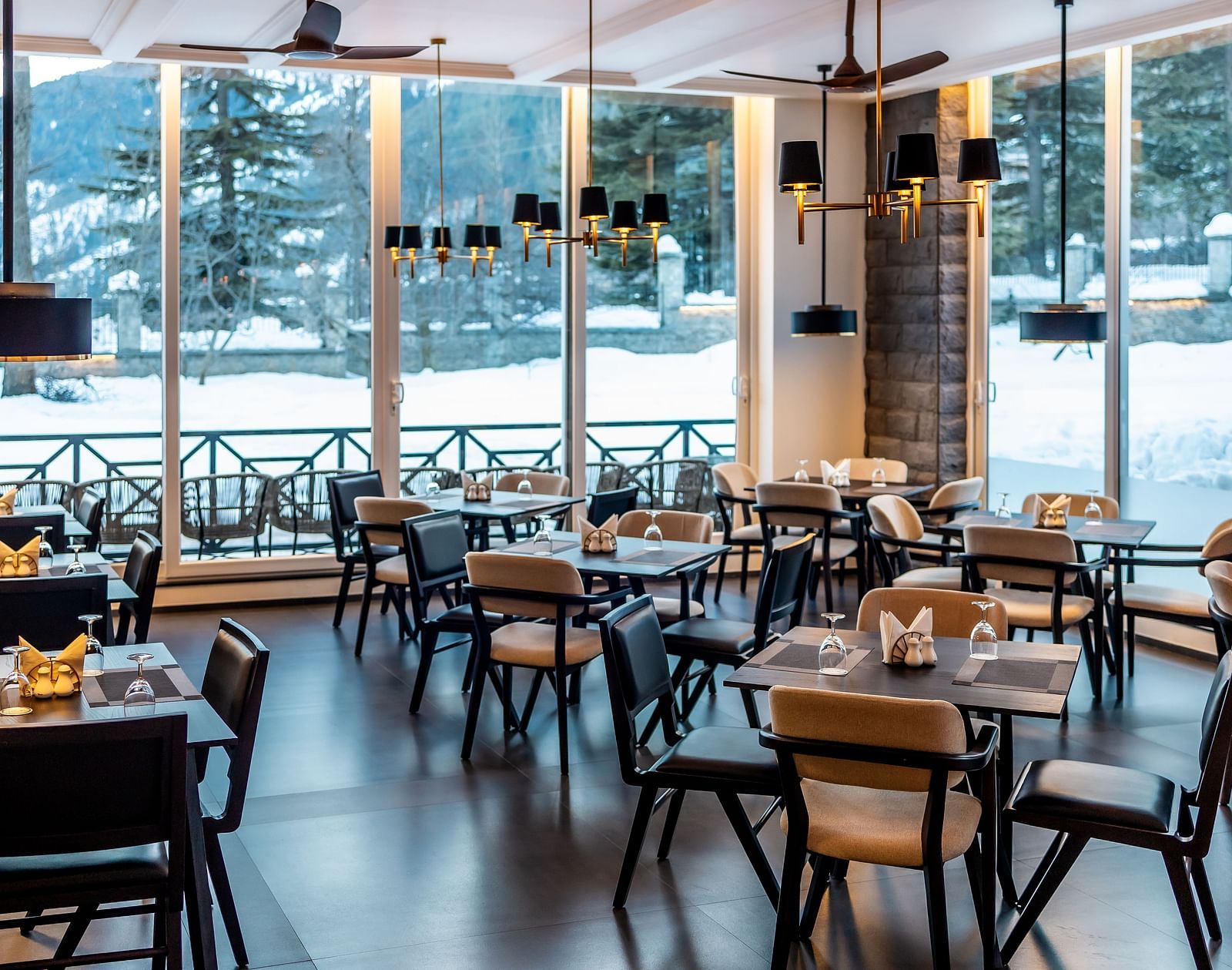 Bright dining area with floor-to-ceiling windows and elegant seating at Nivasana Manali.