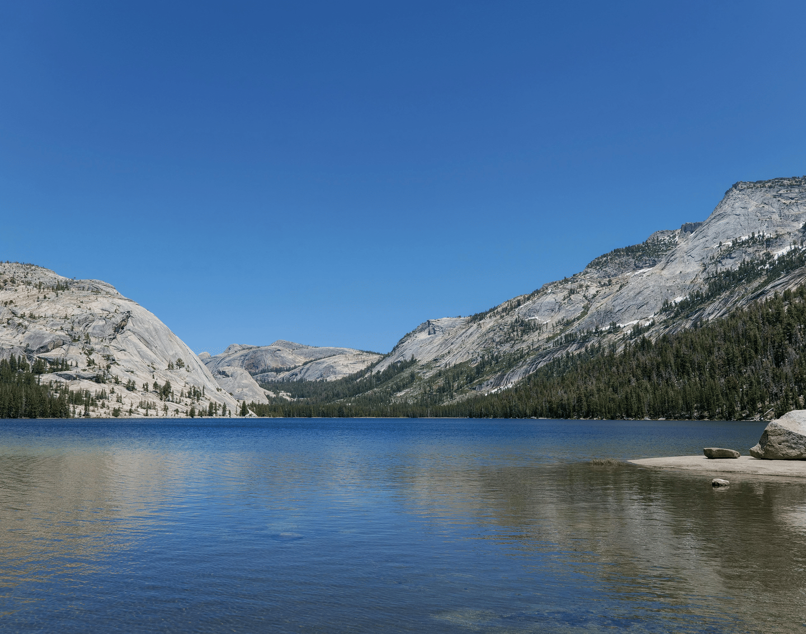 A lake with mountains in the background under a clear sky.