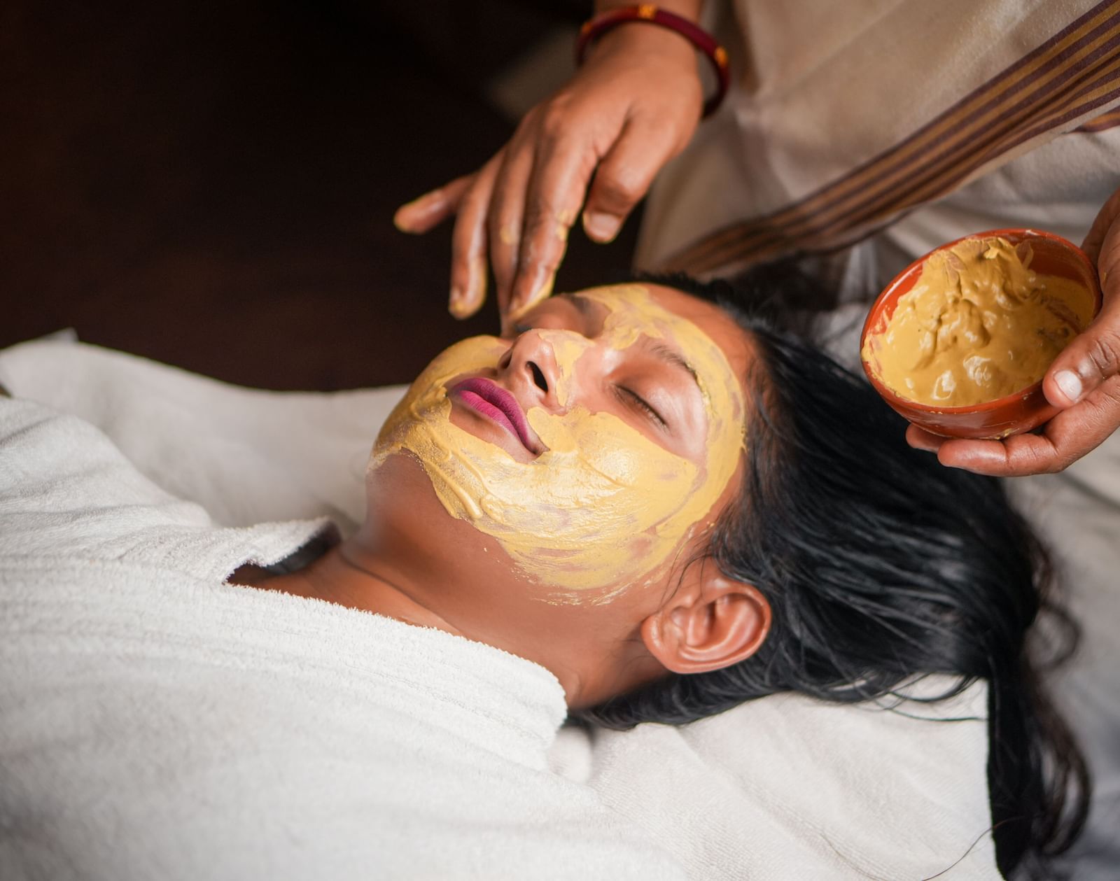 Facial mask application in Vedic Village Spa Resort, featuring a person receiving a natural face pack.