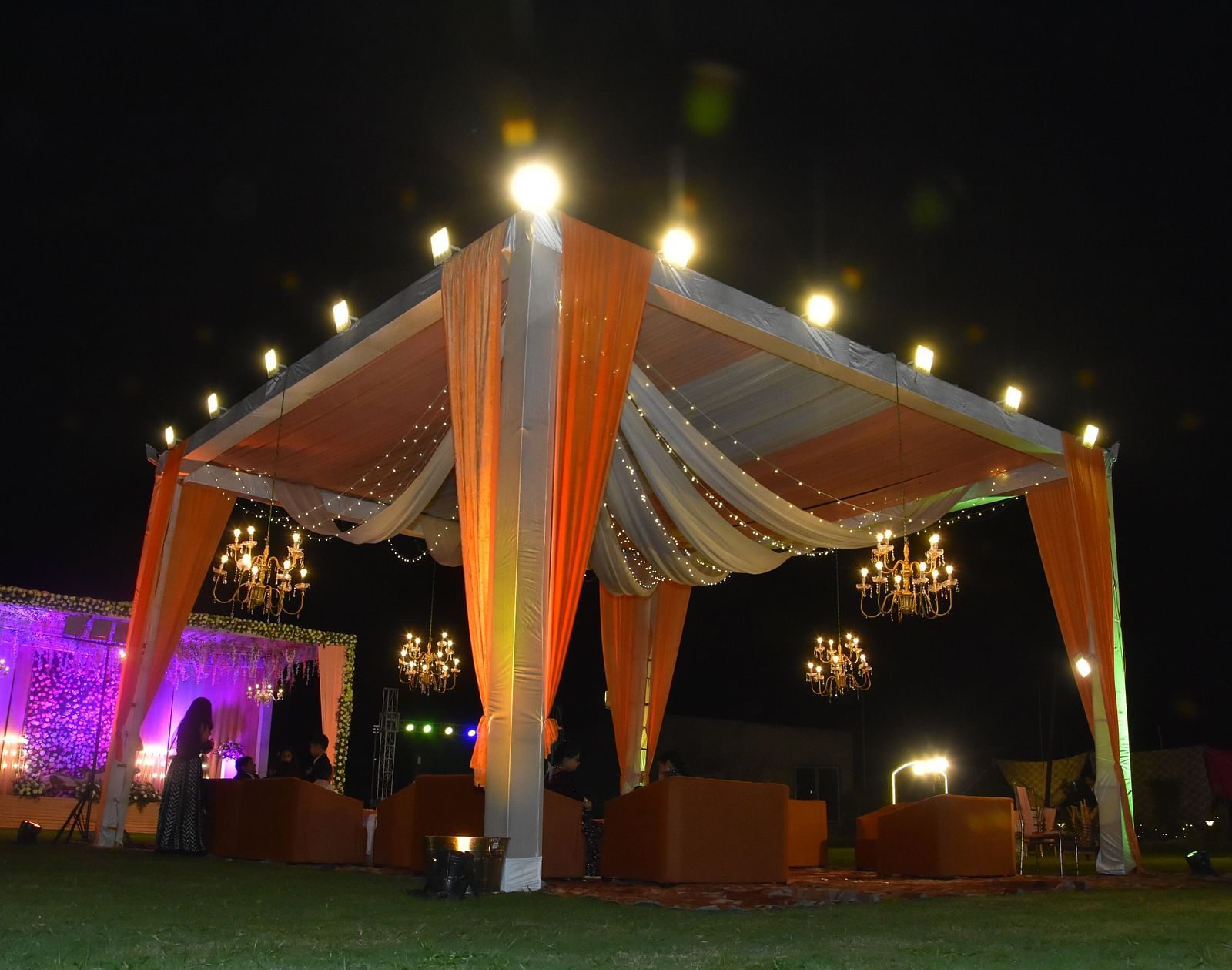 Outdoor event canopy with draped lights and seating at Vedikant Hotels & Resorts with night sky in the background.