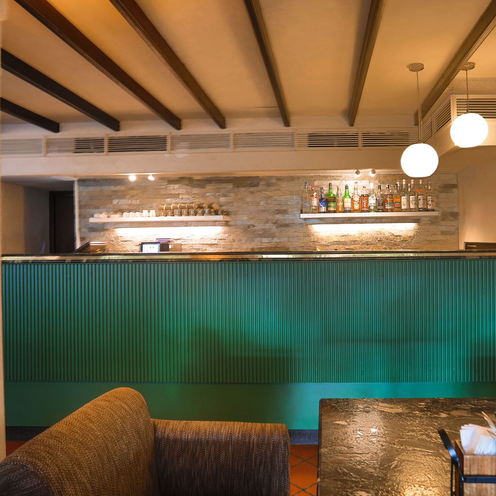 A cosy bar at Shilton International, Kochi, with a well-stocked counter and comfortable seating, ideal for relaxation.
