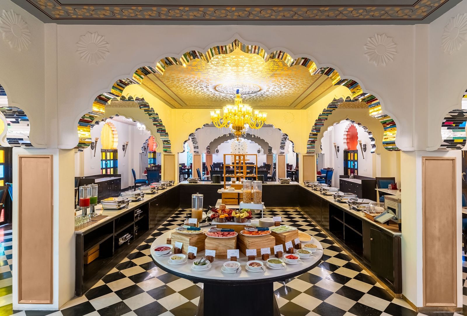 Lavish buffet dining area with black-and-white flooring and chandeliers at Kesar Bagh Palace.