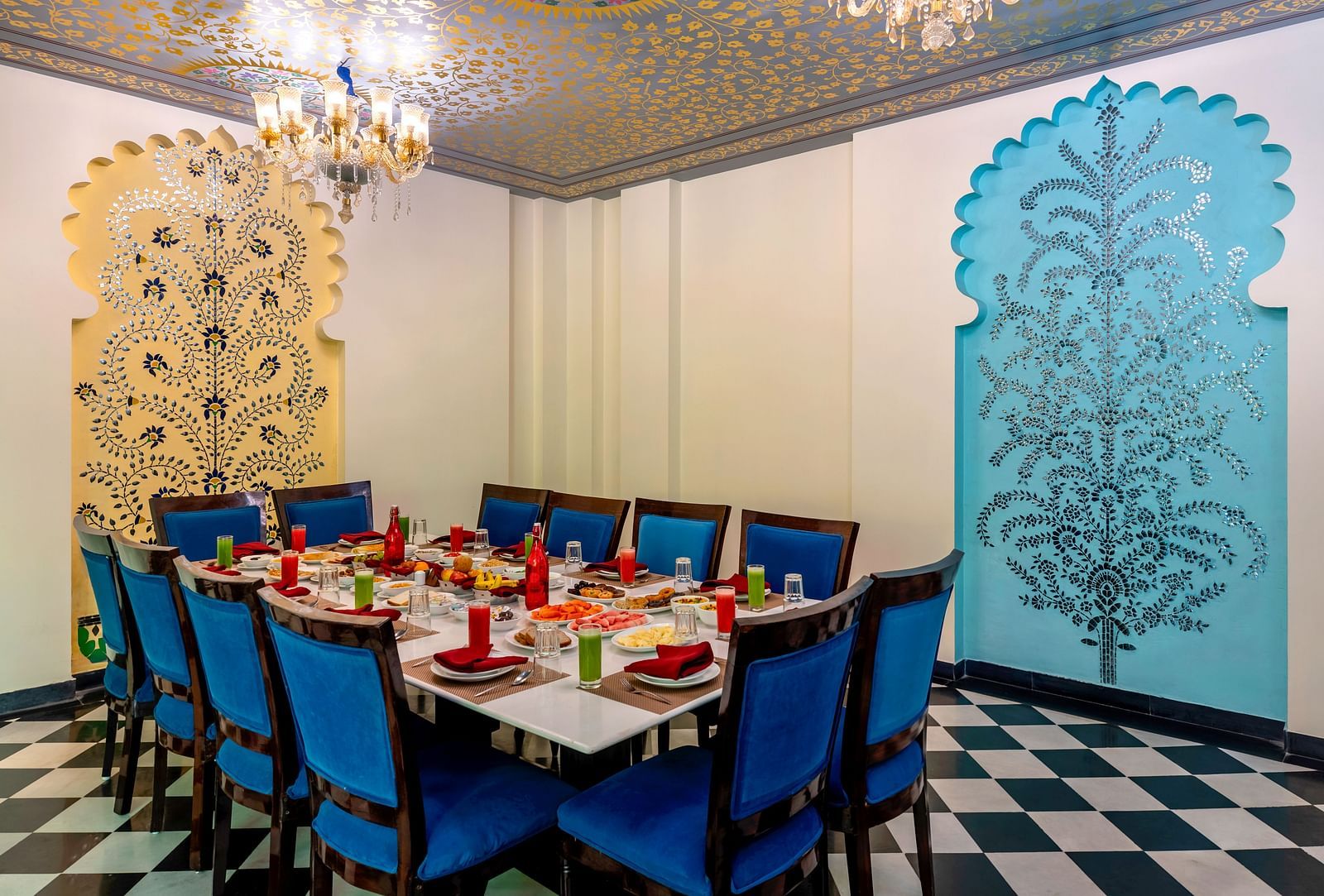Elegant dining setup with blue chairs and Rajasthani wall motifs