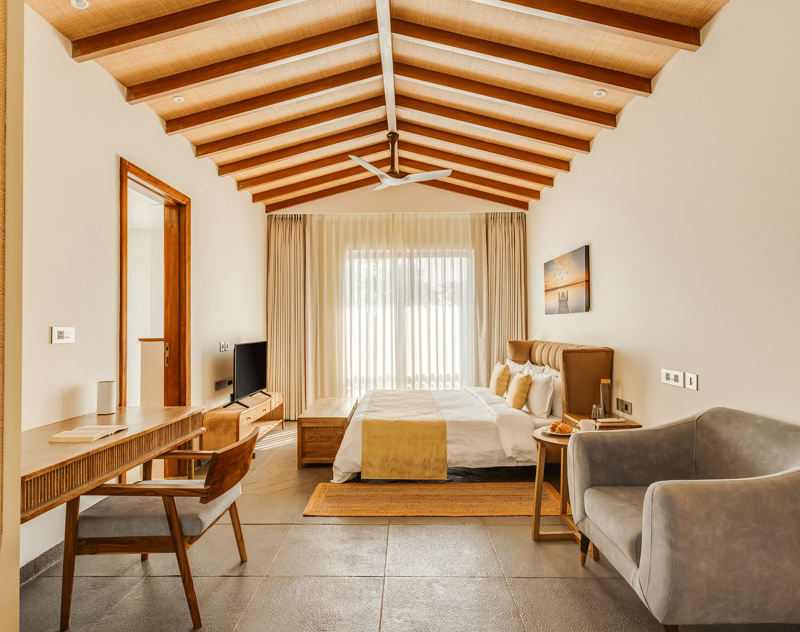 A spacious bedroom with a pitched wooden ceiling, a comfortable bed, seating area, and a bright, airy ambience - BluSalzz Villas - Alocassia, Anjuna