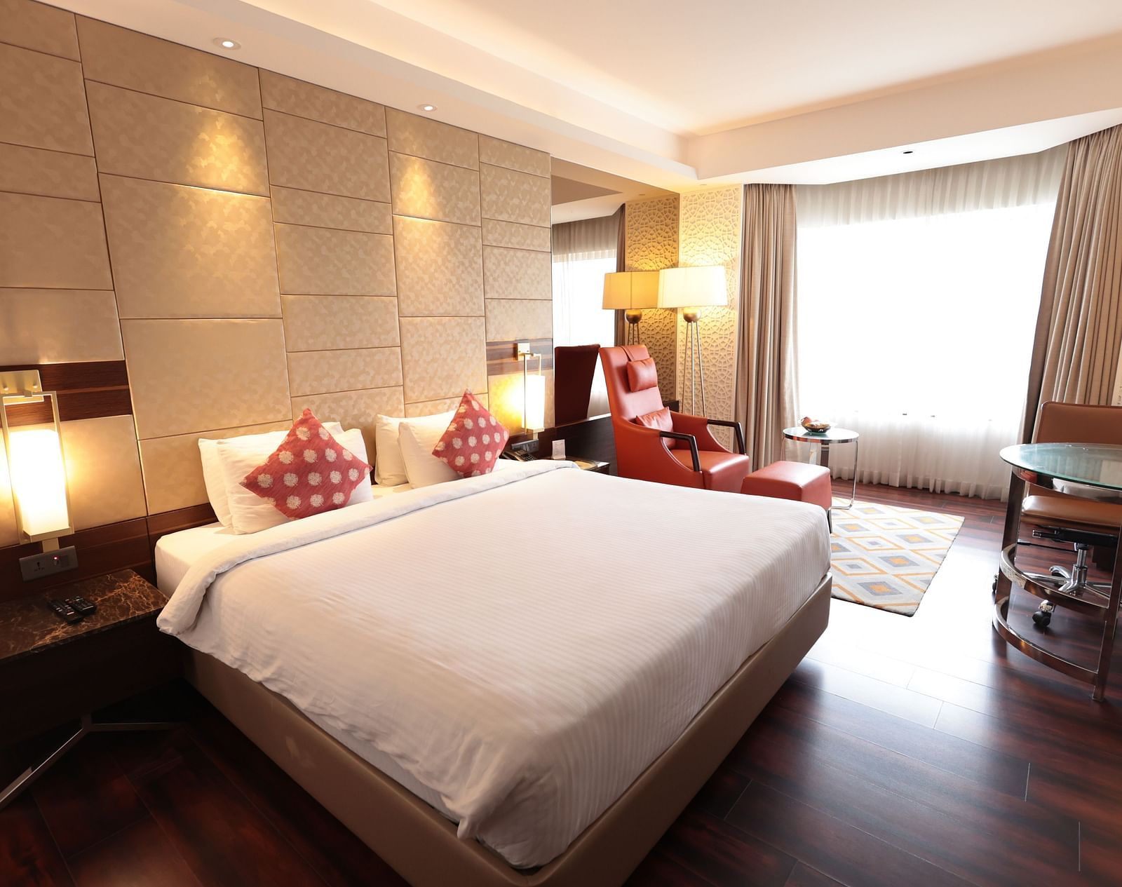 A spacious room with a large bed, a bedside table with a lamp, and curtains pulled to the side of the windows | Cenneys Gateway