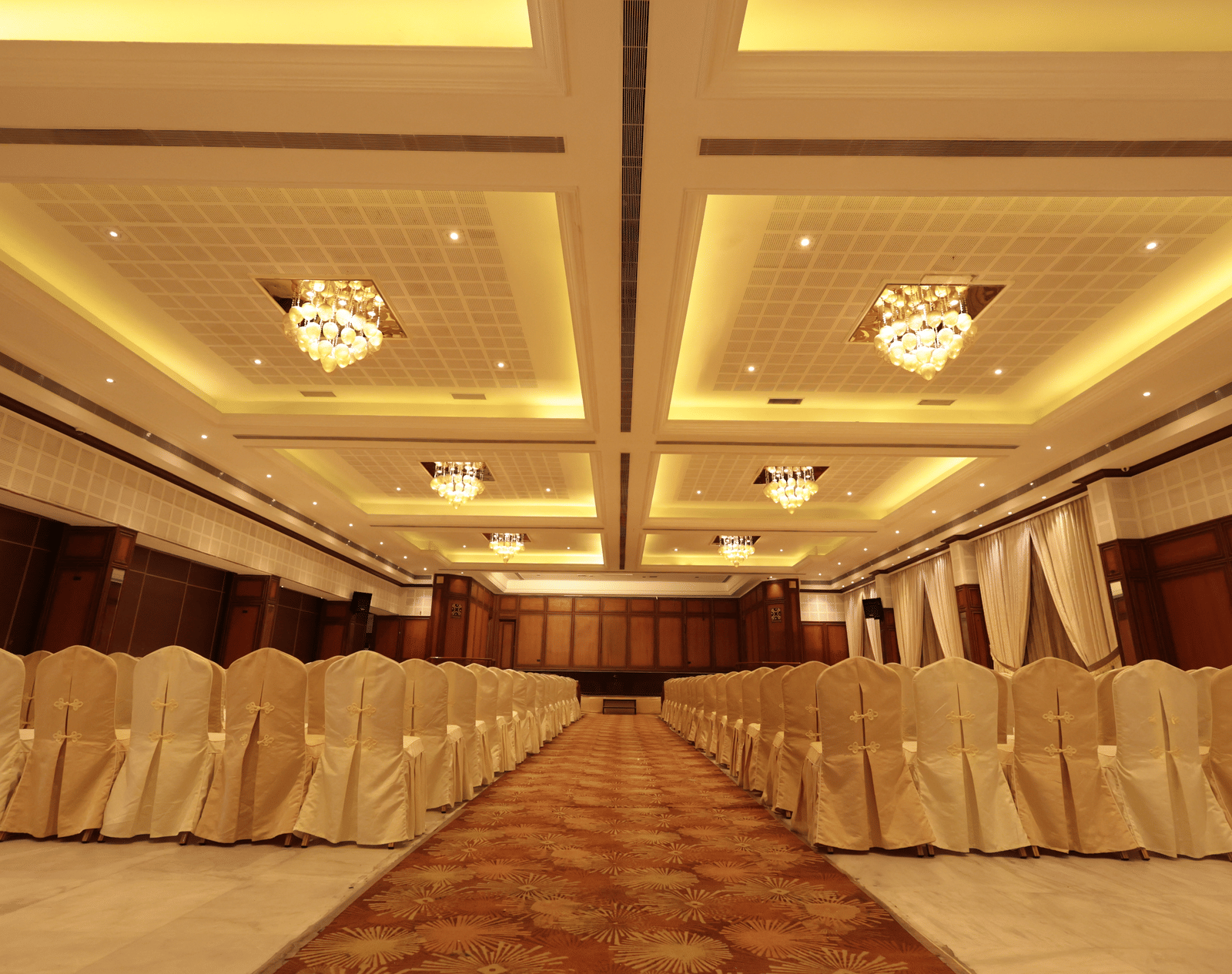 A front view of a banquet hall with chairs arranged on both sides with yellow lighting | Cenneys Gateway