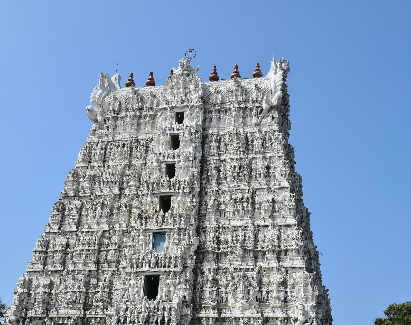 A view from afar of a temple's roof with intricate architecture on it and clear sky in the background.