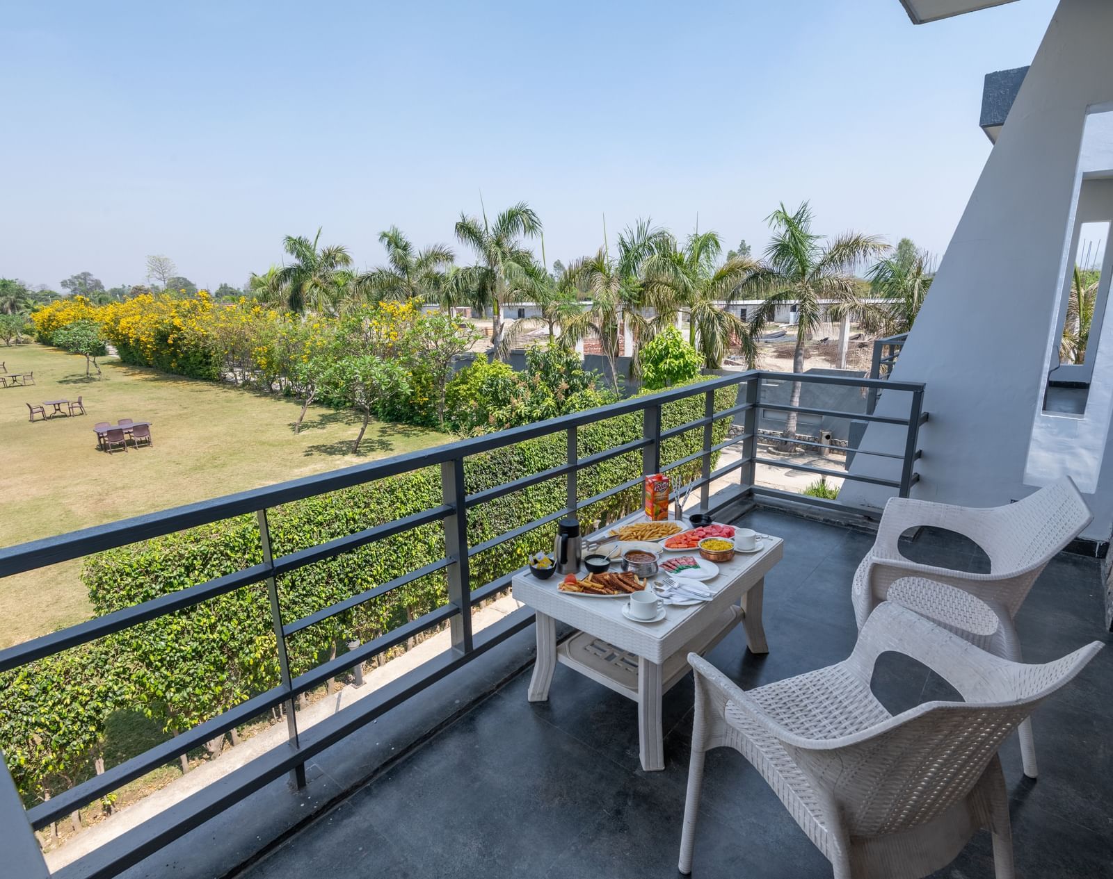 Private balcony setup with chairs and table overlooking open landscape - DLS Forest Vines Resort & Spa, Ramnagar | Best Place to Stay in Jim Corbett
