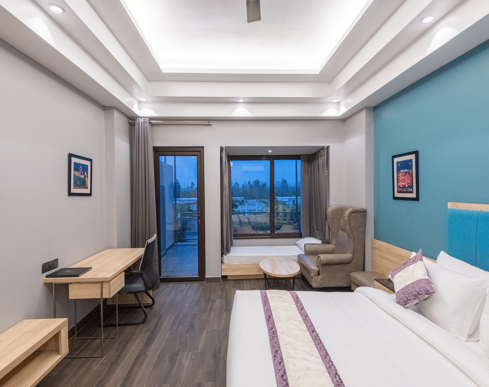 Guest room with cosy bed, reading lights and seating area near balcony - DLS Forest Vines Resort & Spa, Ramnagar (Jim Corbett)