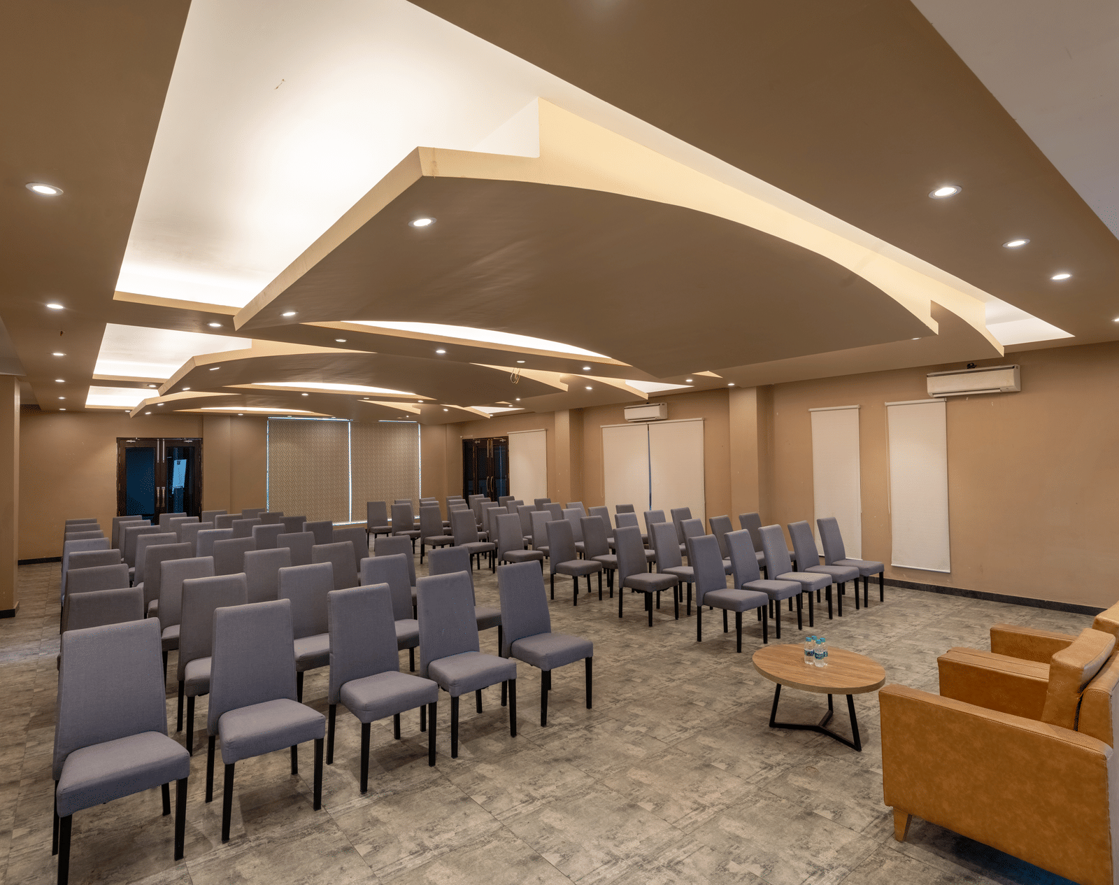 Banquet halls in Jim Corbett at DLS Forest Vines Resort, with cushioned seating arranged on both sides, a plush sofa, and a table placed in front.
