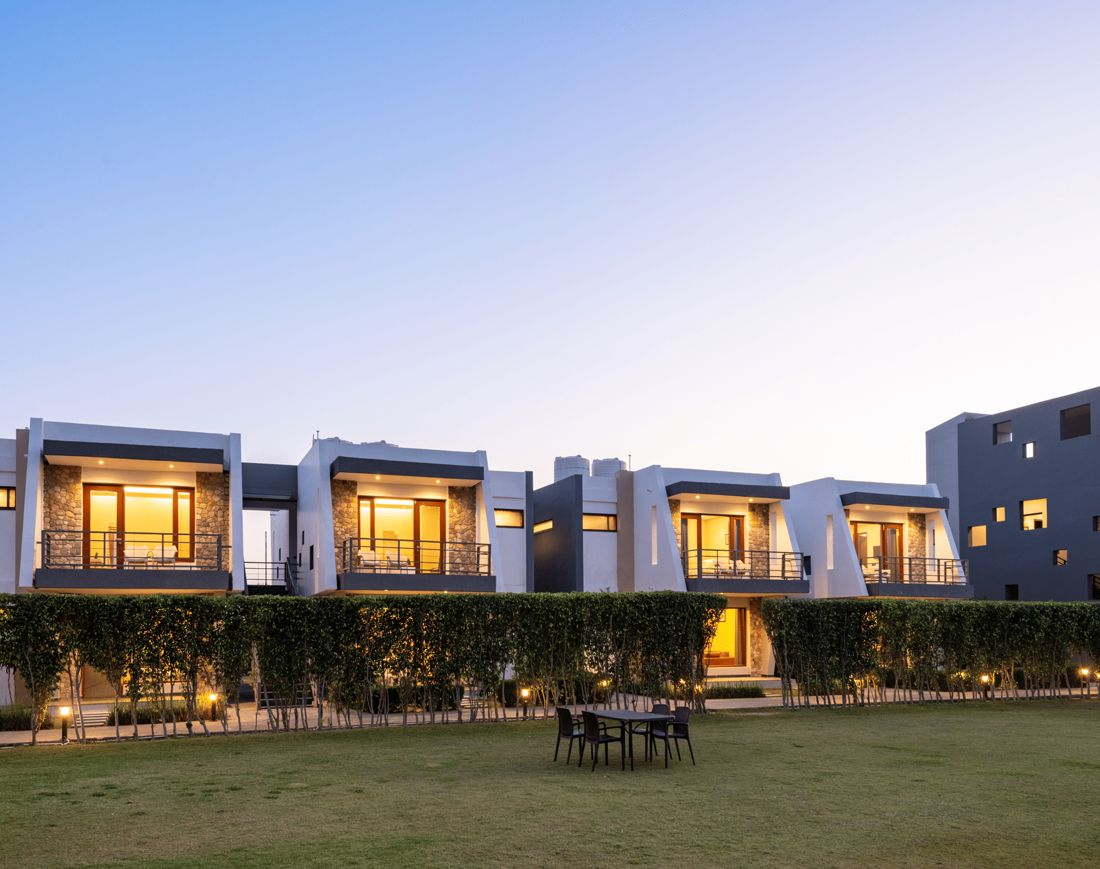 Facade view of DLS Forest Vines Resort, illuminated by warm lights from the windows and doors.