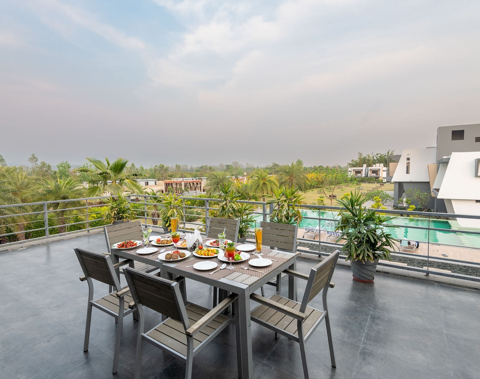 A terrace at DLS Forest Vines Resort with a table for six, beautifully set with an array of dishes.