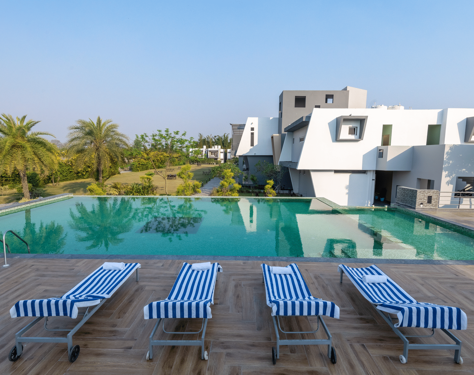 Pool area with lounge chairs placed beside it, offering a view of trees on one side at DLS Forest Vines Resort.