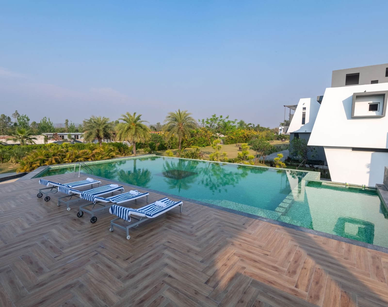 Pool area with lounge chairs placed beside it, offering a view of trees on one side at DLS Forest Vines Resort.