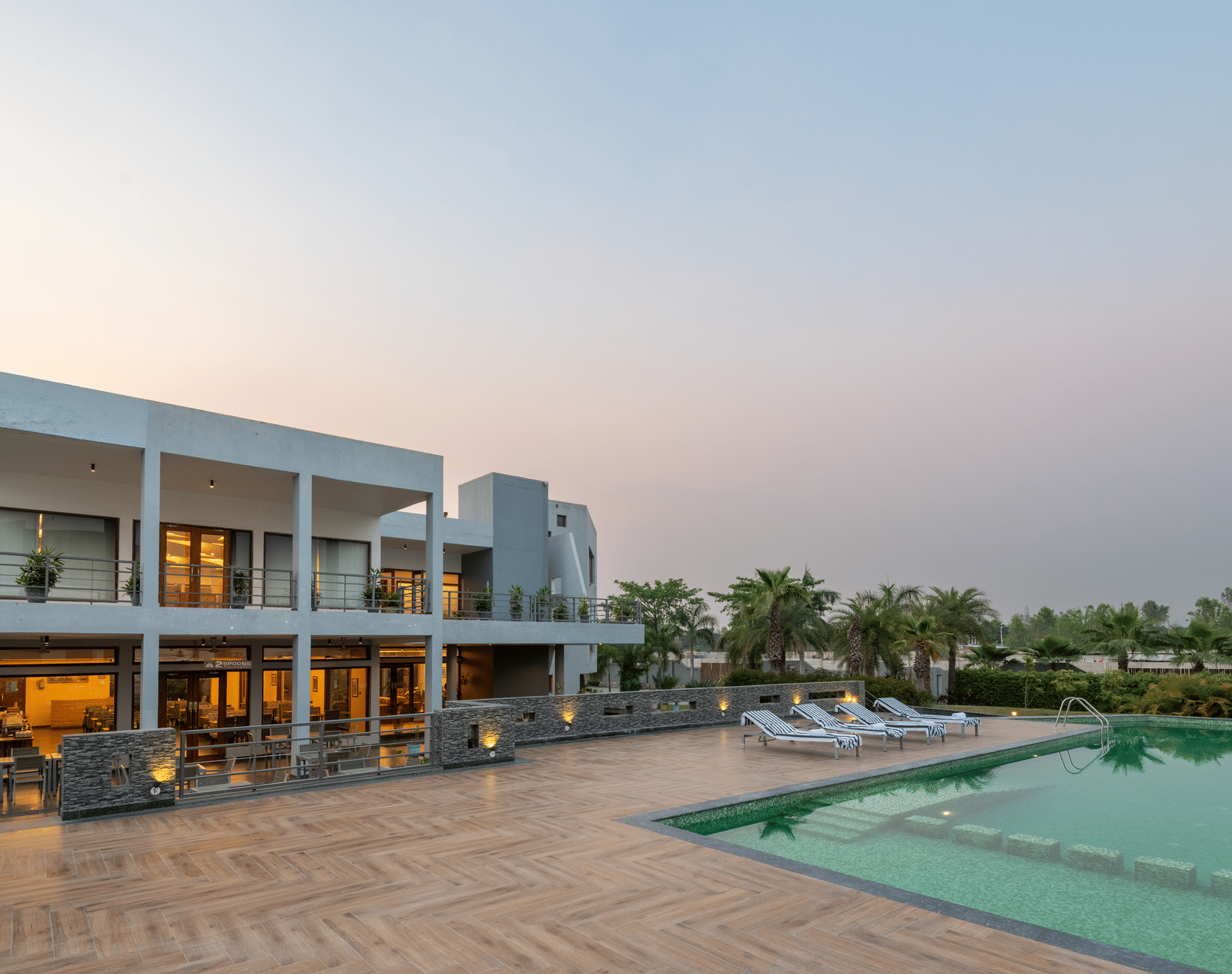 Facade view of DLS Forest Vines Resort on one side and the pool on the other, set against the sky.